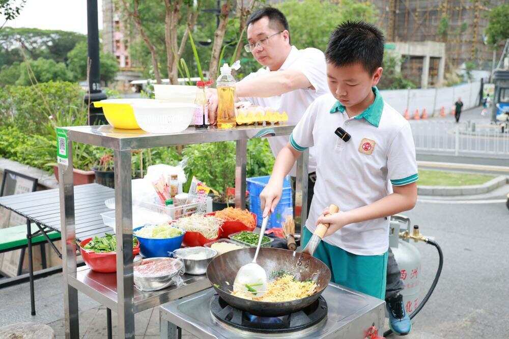 卢子川在炒面，爸爸在一旁协助指导
