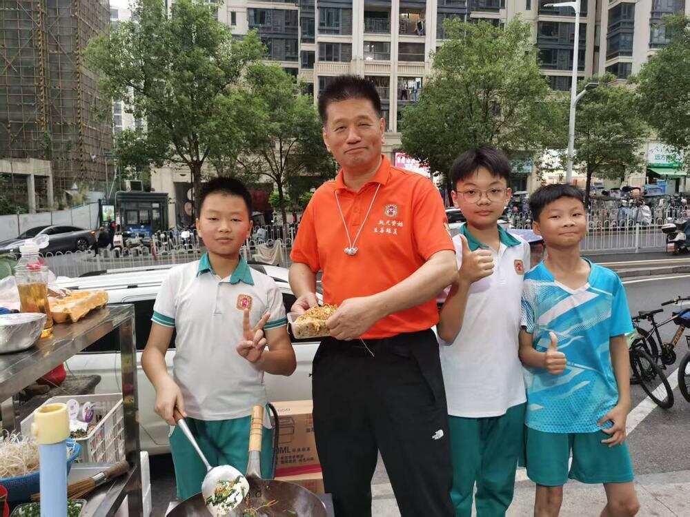 开元学校总校长陈祖力（左二）带着师生来到摊前为卢子川（左一）站台“打call”