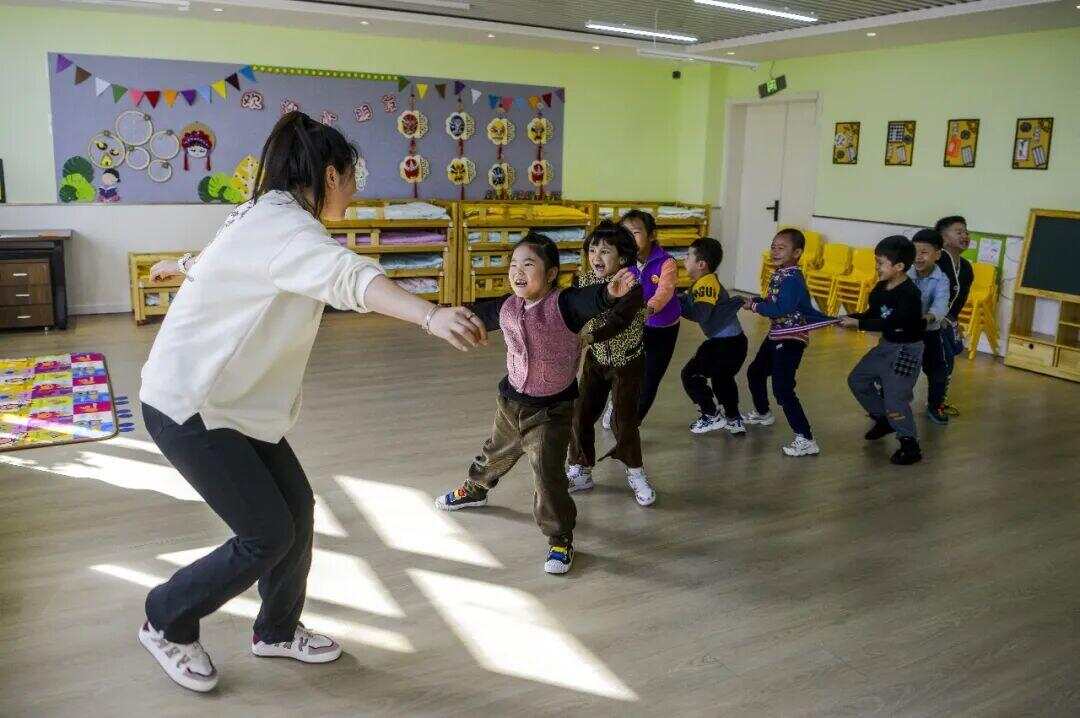 2023年3月10日,新疆乌鲁木齐市第四幼儿园分园,幼儿教师带着小朋友们在教室里做游戏。 资料图片,中新社发 2023年3月10日,新疆乌鲁木齐市第四幼儿园分园,幼儿教师带着小朋友们在教室里做游戏。 资料图片,中新社发